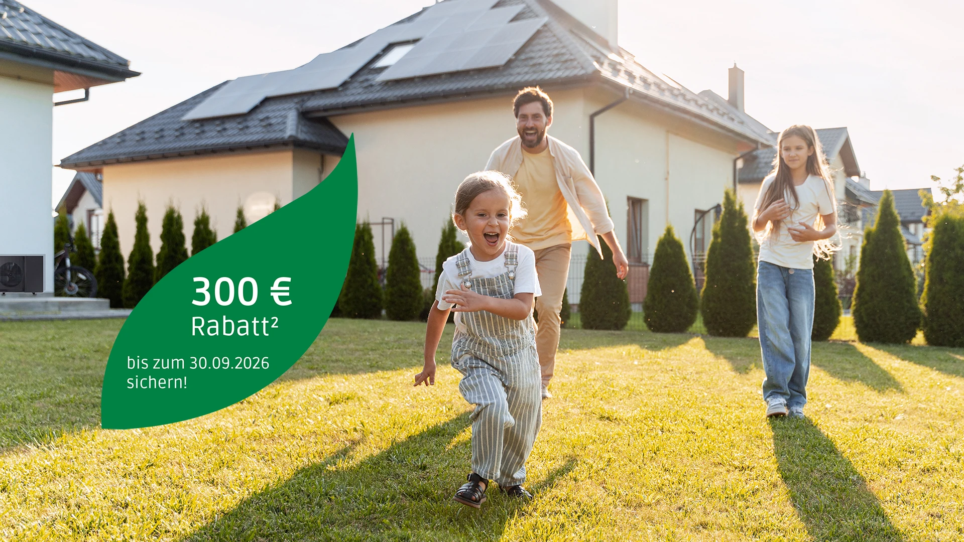 Glückliche Familien vor einem Einfamilienhaus im Garten, auf dem Bild ein Störer mit der Aktion "300 € Rabatt bis zum 30.09.2026 sichern!"